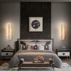 Clérachic matching Selvia wall lights lit either side of a bed, framing a dark fluted headboard panel