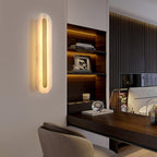Clérachic selvia wall light seen at an angle on a white wall of a study, lit beside a walnut desk nook