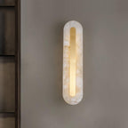 Clérachic selvia wall light lit and centred on a warm grey wall next to a dark shelving unit