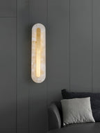 Brass-trimmed alabaster wall light glowing in a soft interior setting