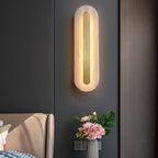 Clérachic full view of the Selvia wall light lit on a charcoal panelled wall above a bedside vase of flowers