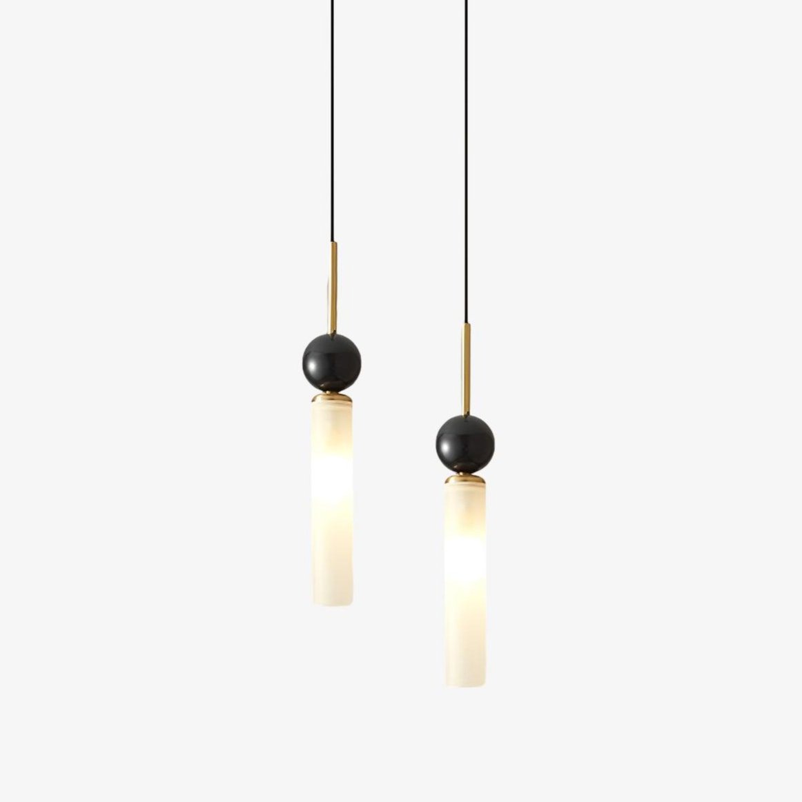 Two Clérachic pendant lights, one on a brass rod and one on black, each pair a dark marble sphere with a frosted glass cylinder.
