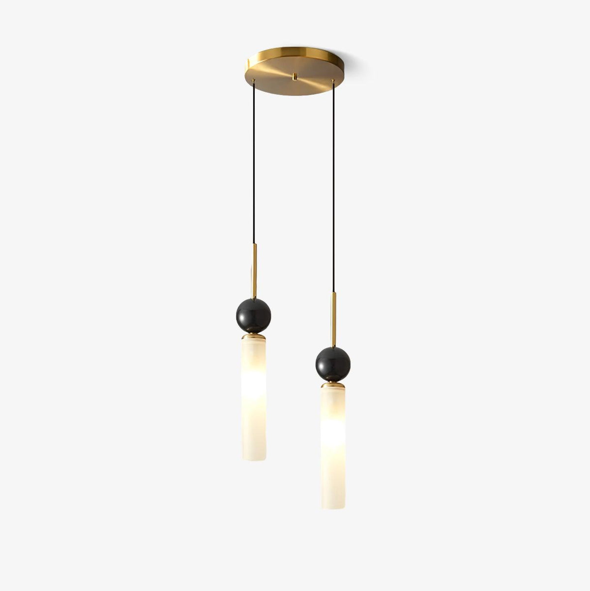 Two Clérachic pendants at staggered lengths hang from one round brass canopy, each glass cylinder topped with a dark marble sphere.