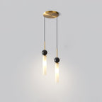 A studio shot of a two-head Clérachic pendant light with a brass canopy, its marble balls and shades at staggered heights.