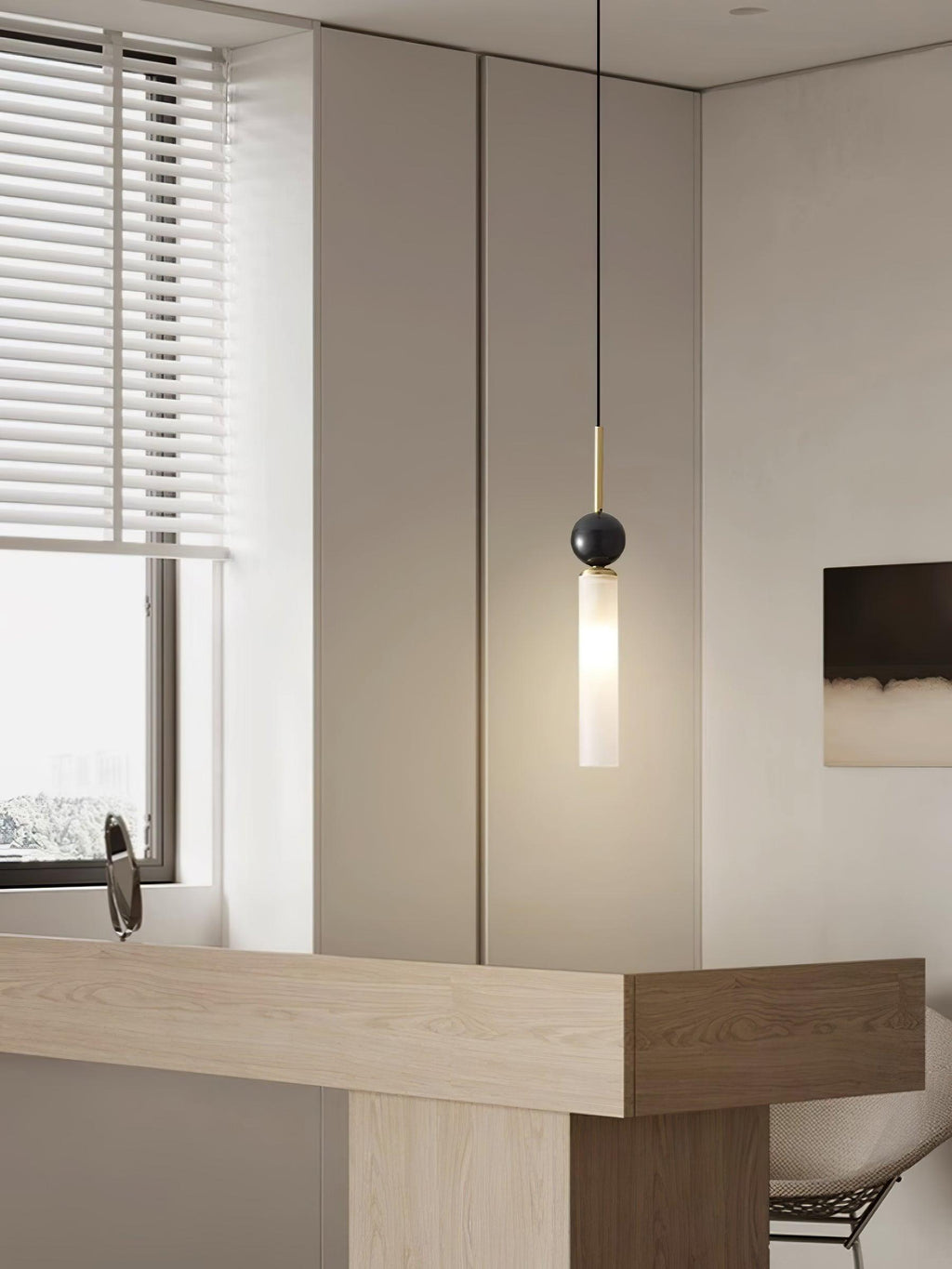 A close-up of a single black marble Clérachic pendant light beside a window with blinds and a light wood countertop.