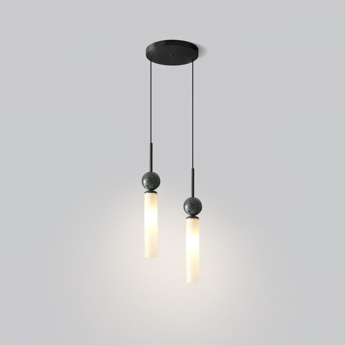 A studio shot of a two-head Clérachic pendant light with a black canopy, its two cylinder shades hanging at different heights.