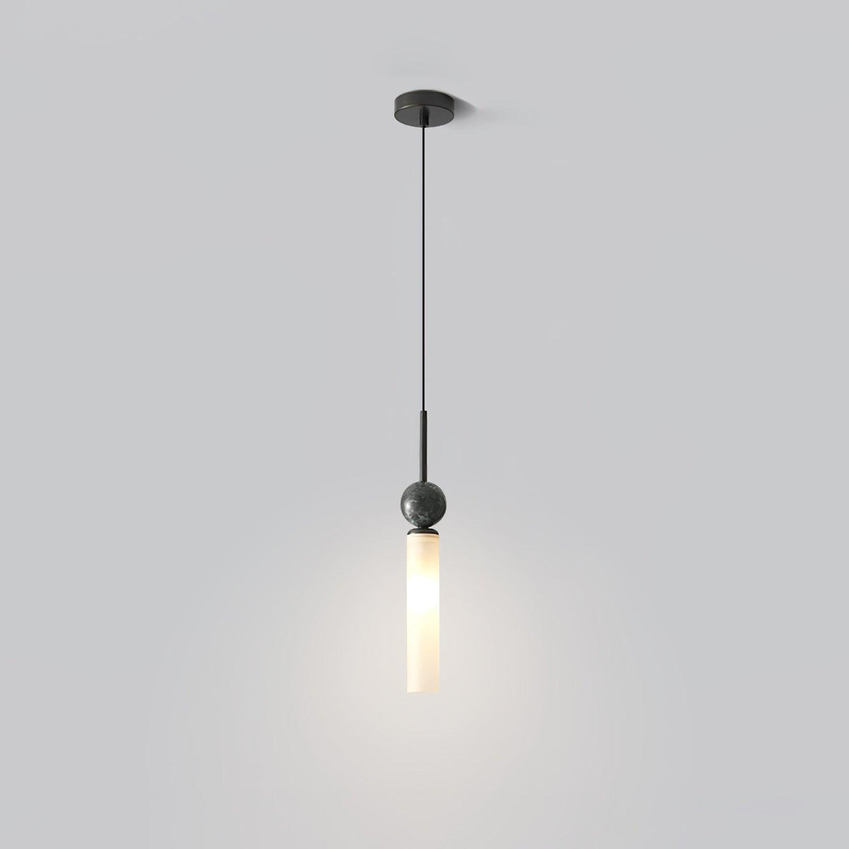 A single Clérachic pendant drops from a round black ceiling canopy, its frosted glass cylinder glowing against a soft grey backdrop.