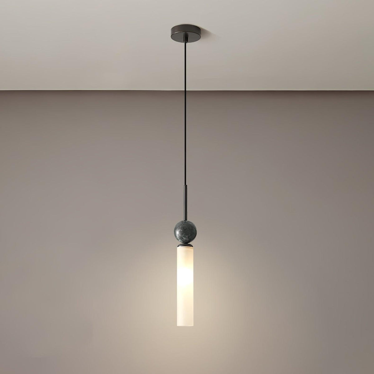 A studio shot of a single black marble Clérachic pendant light against a taupe gradient background, showing the ceiling mount.