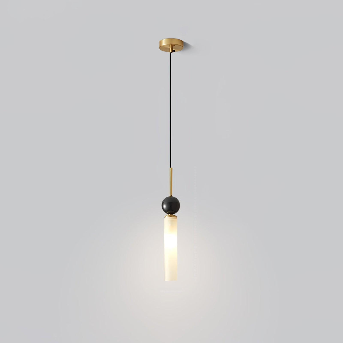 A studio shot of a single Clérachic pendant light on a plain background, showing its brass canopy, marble ball and frosted shade.
