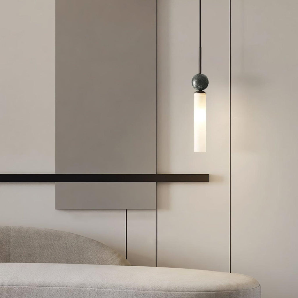 A close-up of a single black marble Clérachic pendant light hanging beside a slim wall bar and an upholstered bench.