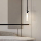A close-up of a single black marble Clérachic pendant light hanging beside a slim wall bar and an upholstered bench.