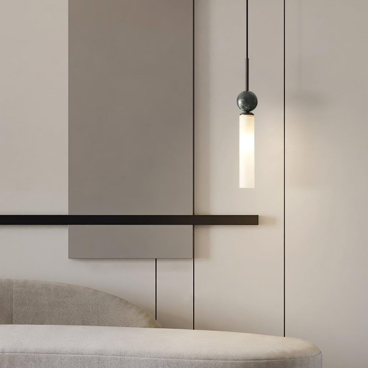 A close-up of a single black marble Clérachic pendant light hanging beside a slim wall bar and an upholstered bench.