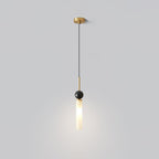 A studio shot of a single-head Clérachic pendant light with a brass canopy and stem, its marble ball and frosted shade lit.