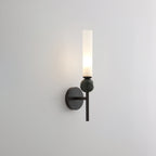 Lit and shown against grey, this Clérachic black-arm wall sconce carries a green marble orb on its arm.