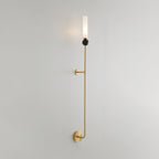 Shown at an angle, full length, this tall Clérachic brass vertical wall light stands against a plain grey background.