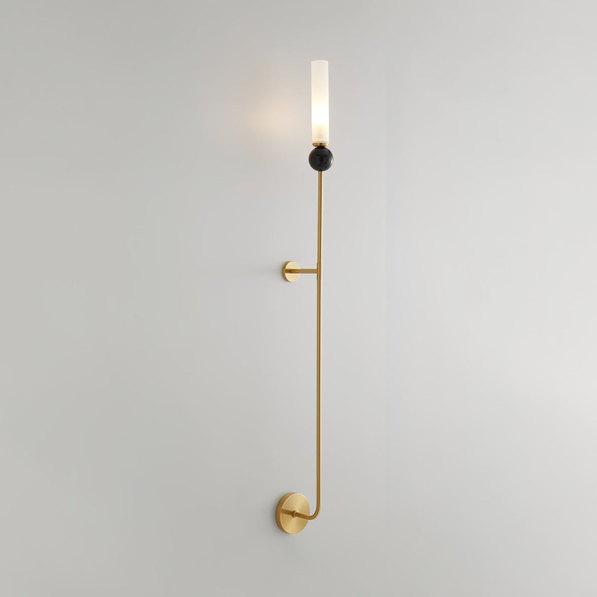 Shown at an angle, full length, this tall Clérachic brass vertical wall light stands against a plain grey background.