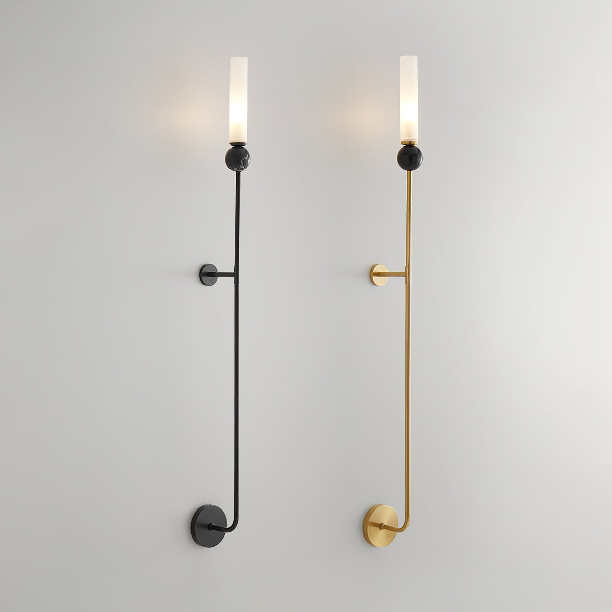 Two tall Clérachic vertical wall lights on white, black and brass side by side, each rod running from a lit tip to a lower wall mount.