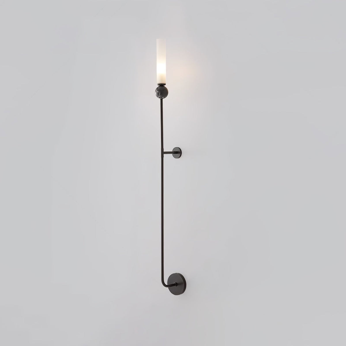 A tall Clérachic black vertical wall light glows at the top, standing full length against a plain grey background.