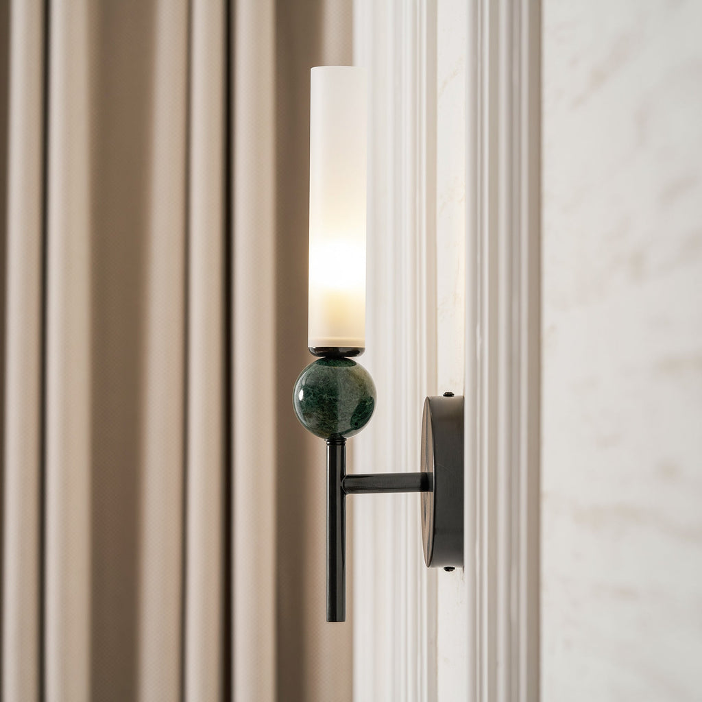 Close crop of the Clérachic wall light beside a linen curtain, the green marble sphere and black backplate filling the frame.