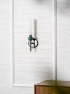 Mounted beside a mirror on panelled walls, the Clérachic wall light is reflected above a low wooden sideboard.