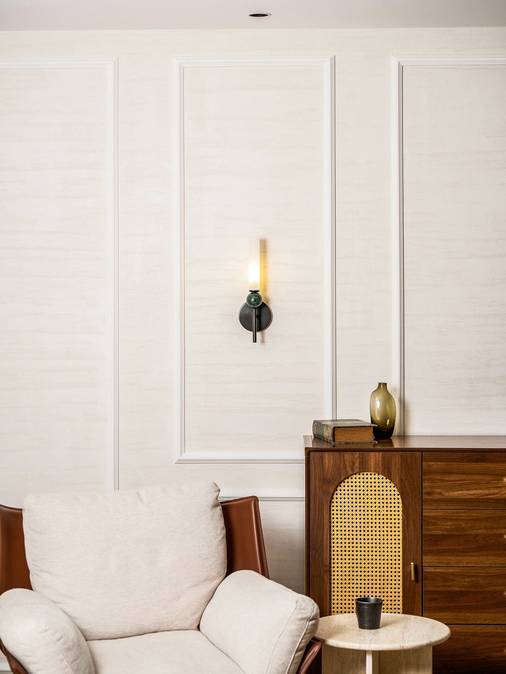 Wide view of a sitting room, the Clérachic wall light on the far panel above a white armchair and a round side table.