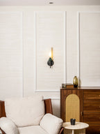 Wide view of a sitting room, the Clérachic wall light on the far panel above a white armchair and a round side table.