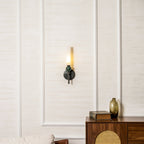 The Clérachic wall light on the left of the frame, a sideboard with a book and a glass vase to the right.