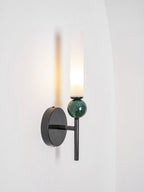 Three-quarter view of the lit Clérachic wall light, the black disc set back from the green marble and glass in front.