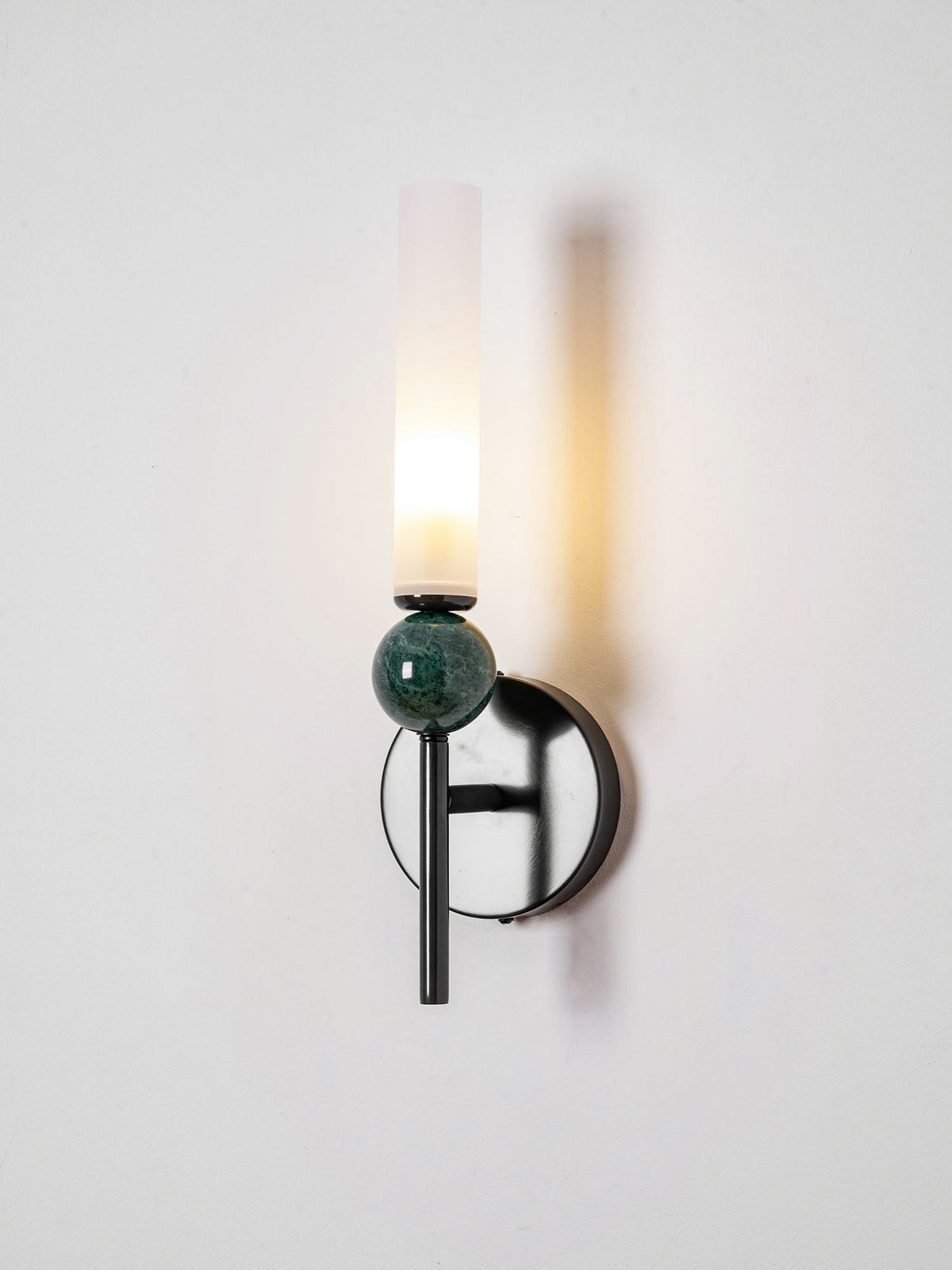 Seen from the side, the arm and ring of the Clérachic wall light are visible behind the lit frosted cylinder.