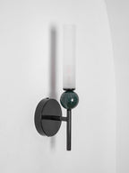 Unlit and angled, the Clérachic wall light shows its clear glass cylinder, green marble sphere and black disc backplate.