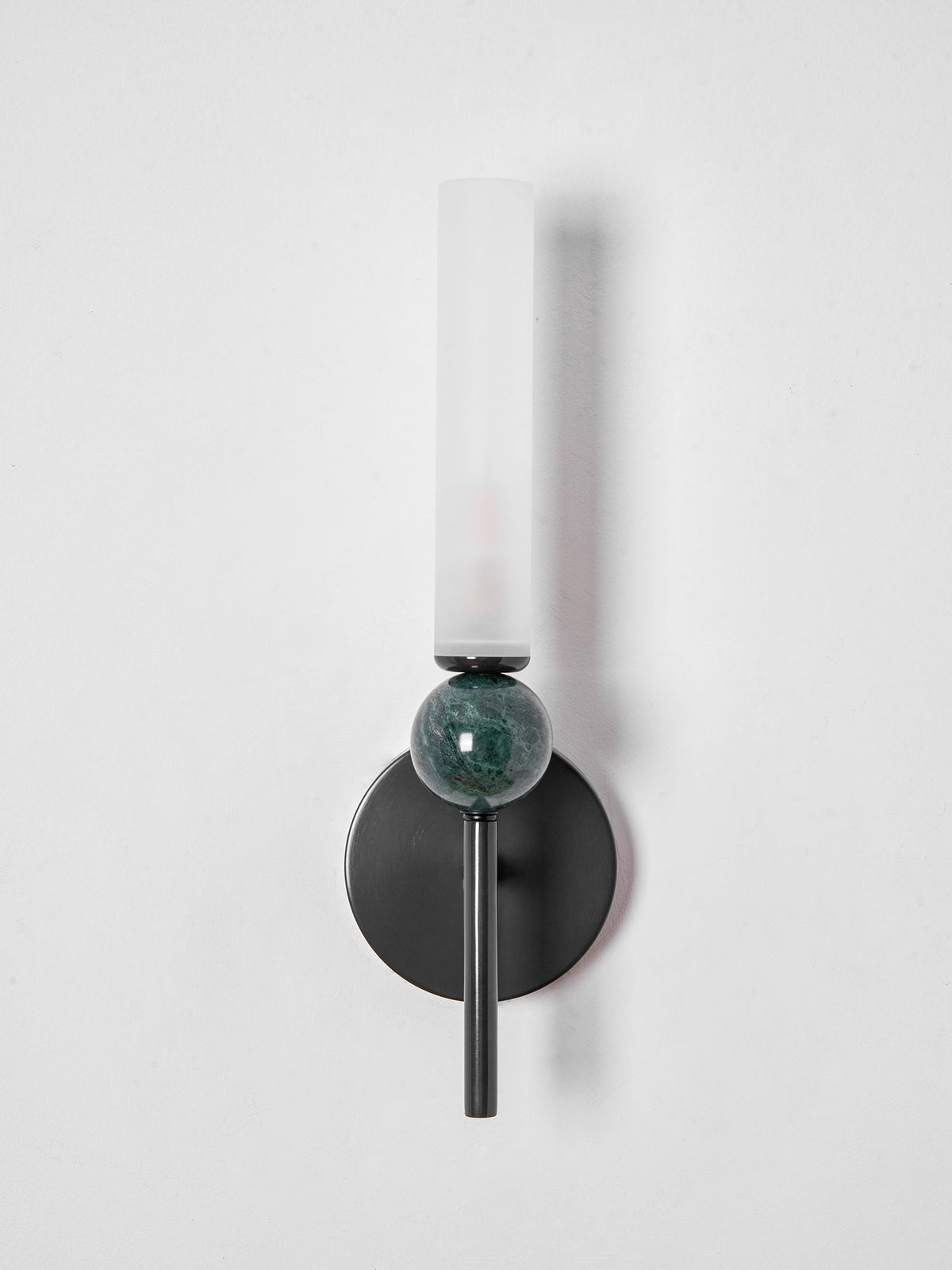Straight-on and unlit, the frosted cylinder of the Clérachic wall light sits above its veined green marble sphere.
