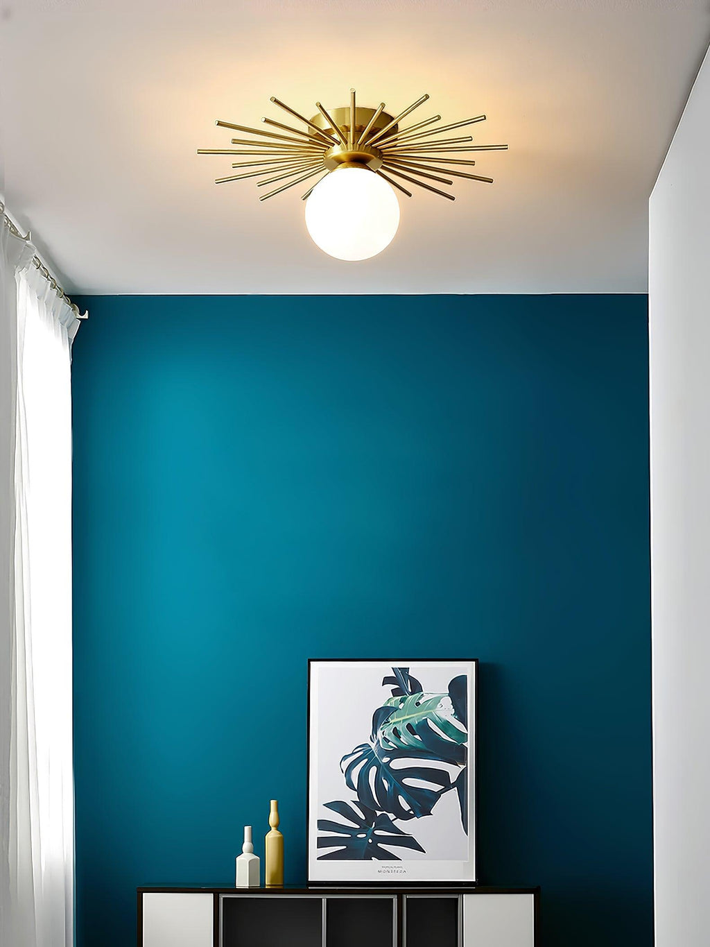 Above a teal wall with a leaf print and bottles on a credenza, this Clérachic ceiling light glows softly.