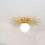 This Clérachic ceiling light sits near crown moulding, its brass rods and globe caught at a close angle.
