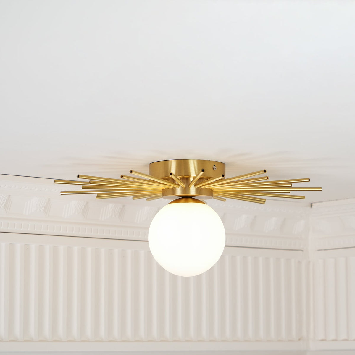 Close view of the round mounting plate on this Clérachic ceiling light, moulding visible on the wall below.