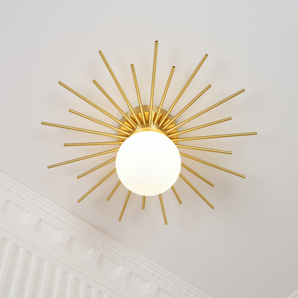 On a wall near ornate crown moulding, this Clérachic wall light shows its full sunburst of brass rods.