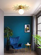 A teal living room wall and a blue velvet armchair sit beneath this Clérachic ceiling light.