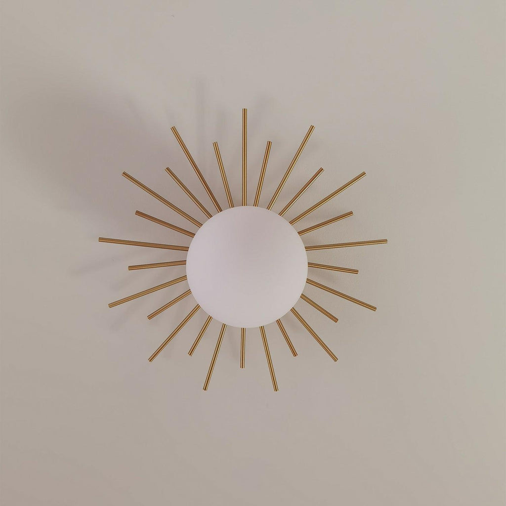 On a plain wall, this Clérachic wall light spreads its brass rays around a central frosted glass globe.