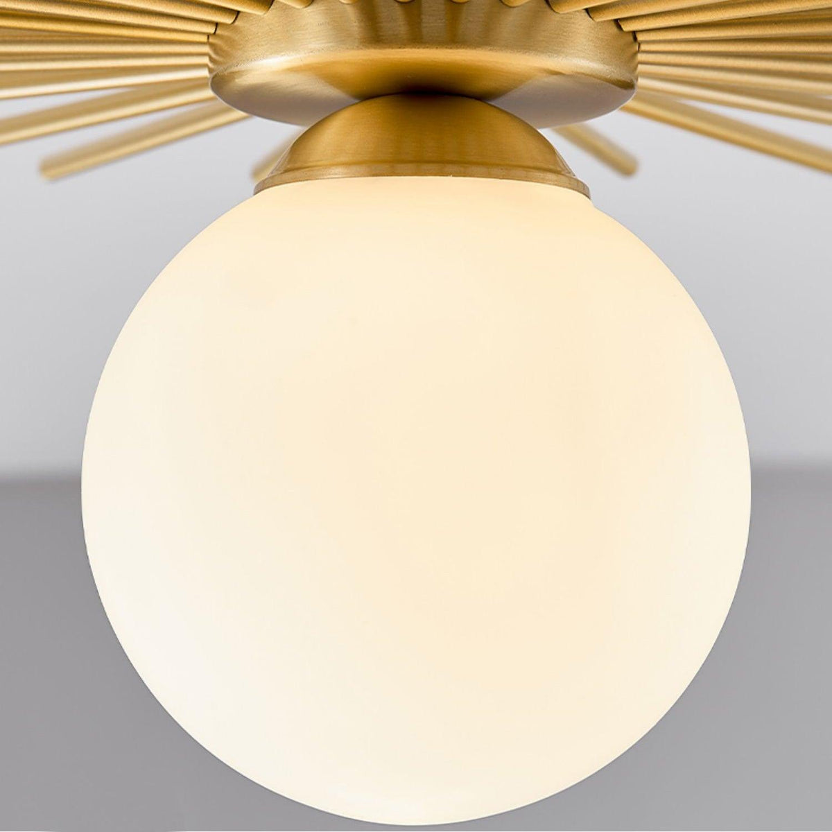 Close view of the frosted glass globe on this Clérachic ceiling light, its brass canopy visible above.