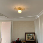 This Clérachic ceiling light lights a small room papered in a pale damask print, a framed painting below.