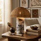 This rattan table lamp from Clérachic lit on a wood side table with a magnifying glass and a stack of old books.