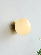 Wall sconce with glass diffuser and slim metal base, lit