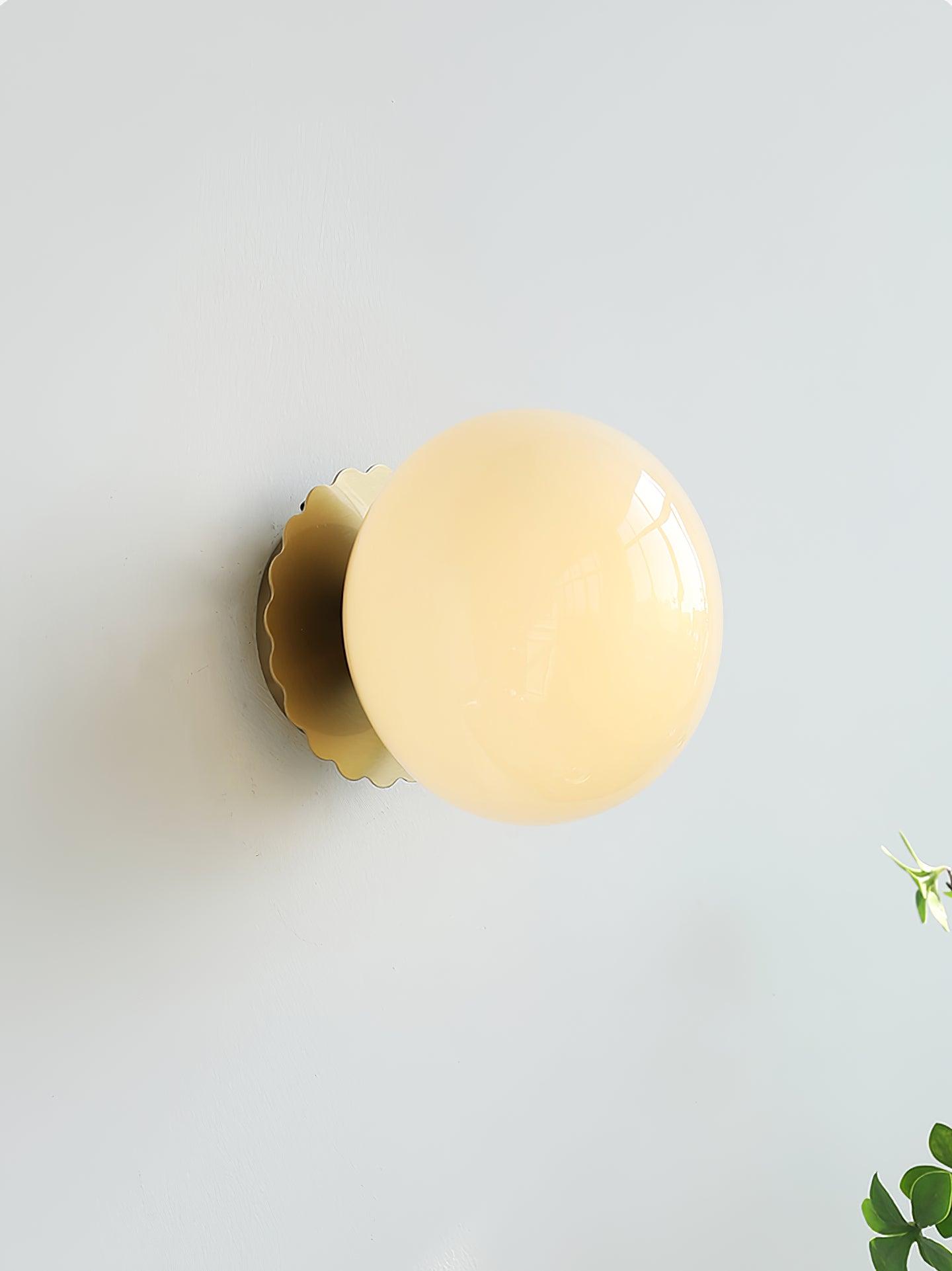 Wall sconce with glass diffuser and slim metal base, lit