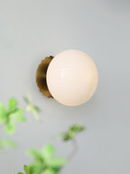 Marshmallow glass sconce glowing warm in a styled space