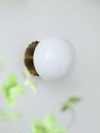 Tinted glass sconce glowing warm on a bedroom wall