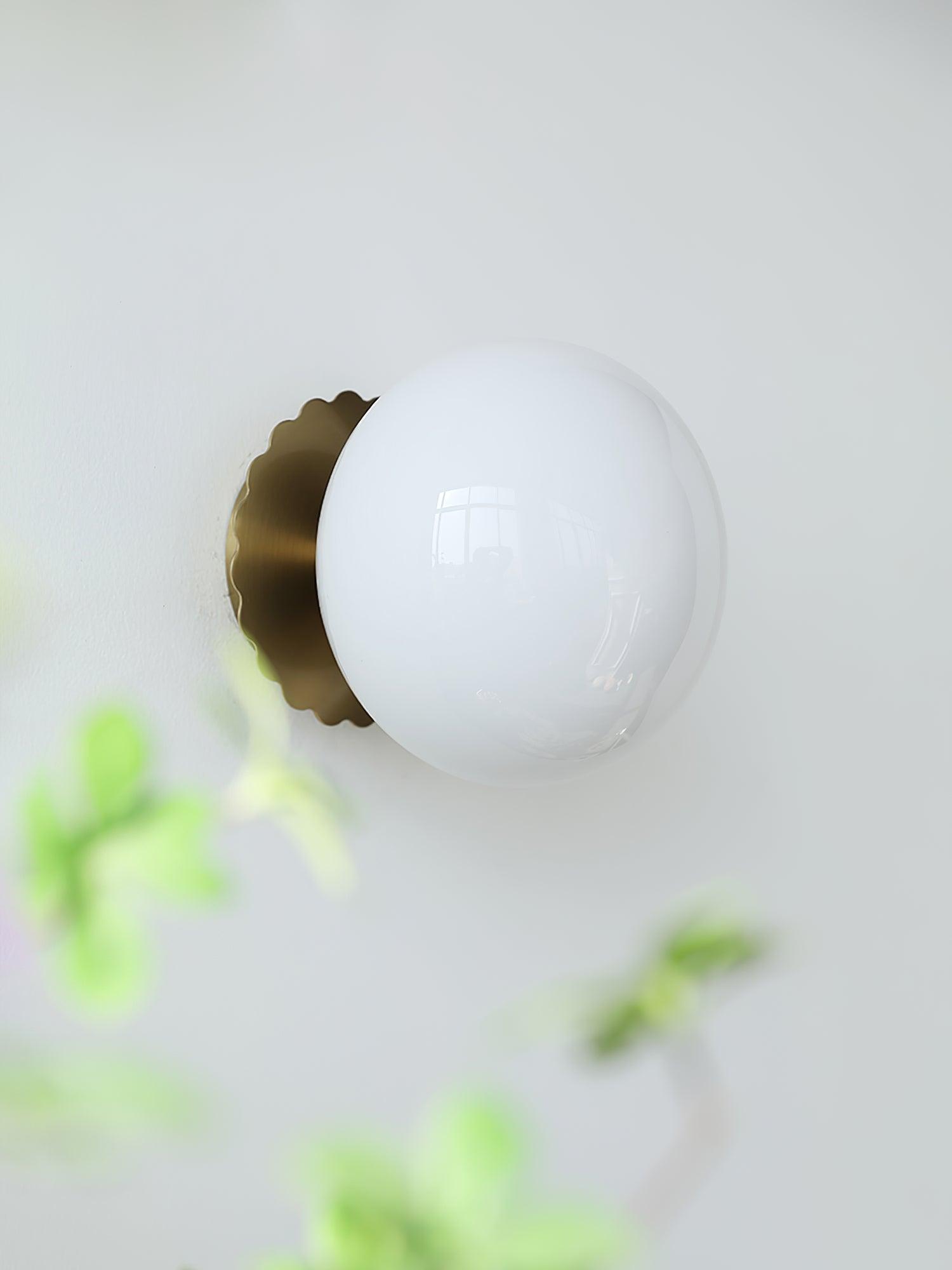 Tinted glass sconce glowing warm on a bedroom wall