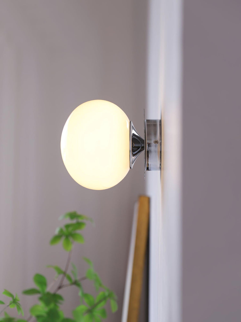 Marshmallow glass sconce shown lit against a neutral wall