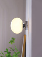 Marshmallow glass sconce shown lit against a neutral wall