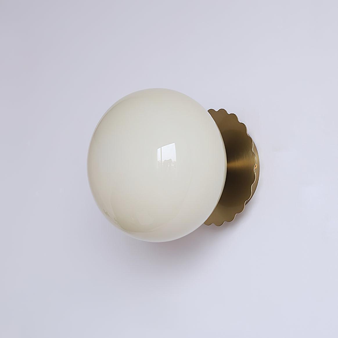 Tinted glass wall sconce glowing soft and warm on a wall