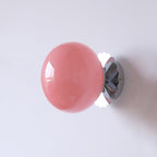 Rounded glass wall sconce glowing warm against a pale wall