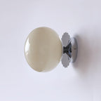 Wall sconce with tinted glass shade mounted beside a mirror